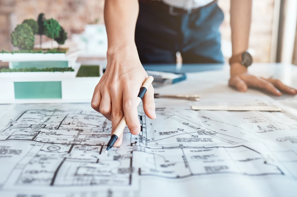 Architecte, main et plan sur papier dans le bureau avec la conception de la propriété, la planification et le crayon pour examen